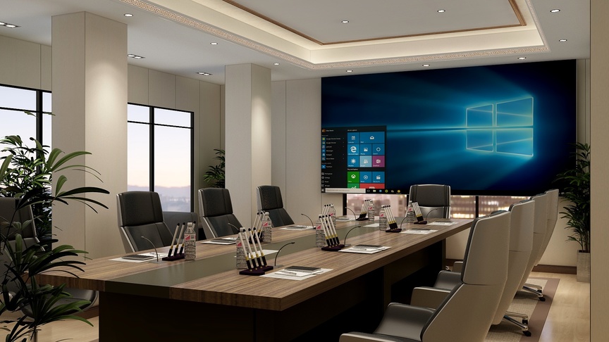 这是一个会议室，墙壁上有一块大屏幕，屏幕上面是Windows10的标志和开始菜单。屏幕下方有一排类似电脑显示器的屏幕。会议室的桌子上放着笔记本电脑和几支笔，桌子周围摆放着黑色的椅子。会议室的顶部装饰有白色的灯带。墙壁的另一侧设有一扇大窗户，窗帘半开，阳光从窗户洒进来，照亮了室内。在窗户的旁边设有一张白色的门。会议室的装修风格现代、简洁。